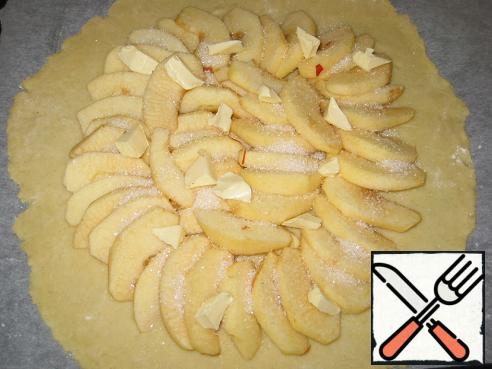 Apples to lay out circles a little at each other, retreating from the edge of 4 cm, sprinkle with a little sugar (about 2 tbsp) on top lay small pieces of butter.