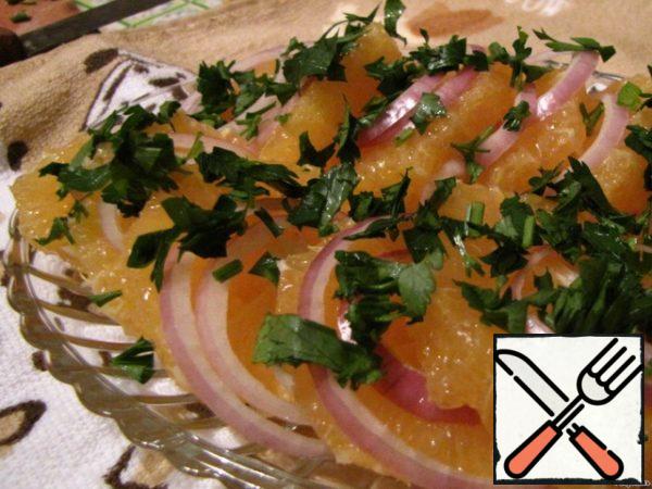 Orange cut into slices, spread on a dish. Sprinkle with onion rings and chopped parsley.