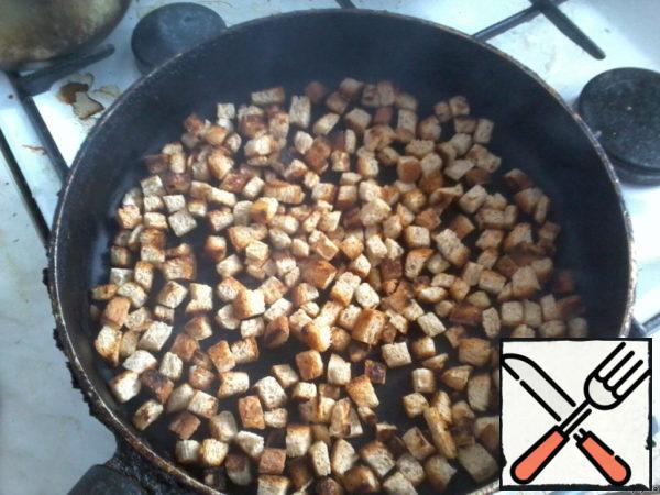 Cut the white bread into cubes and fry in a pan to the state of crackers.