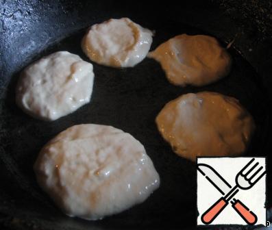 In the pan pour the oil, spread with a tablespoon of dough.