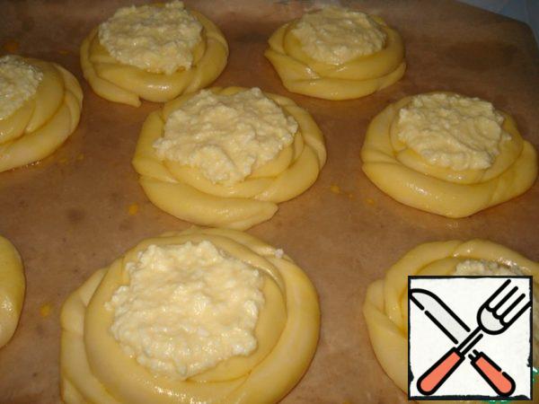 Push in the center of the spirals pits and put the filling. Put on proofing in a warm place for an hour. Bake at 200 °C.