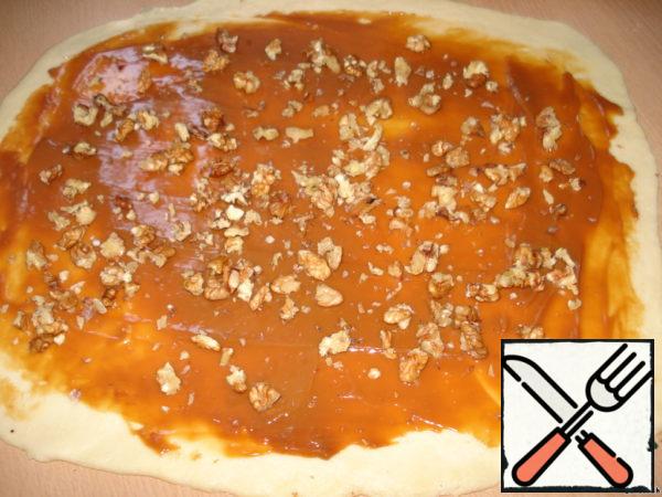 On the dough layer spread condensed milk and sprinkle with nuts.