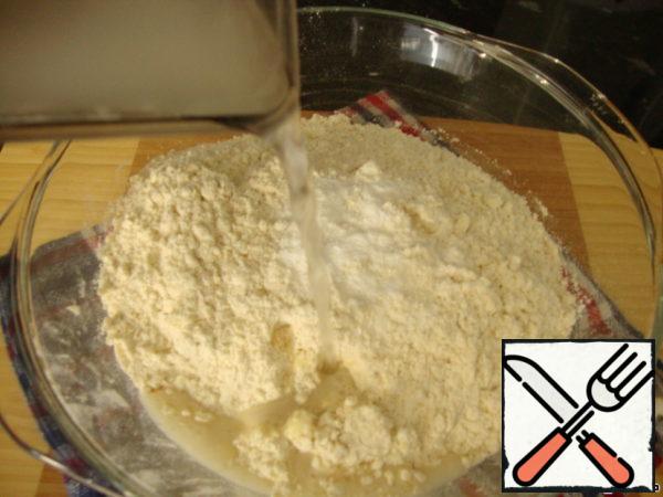 Gradually pour in water, knead a soft dough. You may need more or less water, it depends on the moisture content of the flour, so pour in the water gradually to determine the amount of liquid in the process.
