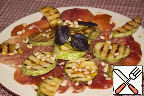 Sprinkle with pine nuts, decorate with sprigs of Basil and enjoy a stunning combination of ham and zucchini on the grill.