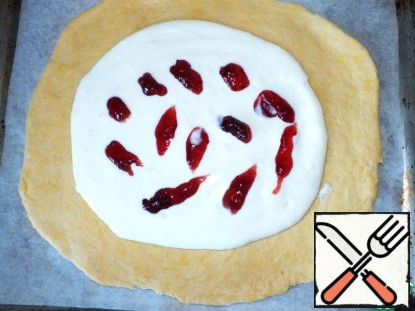 Roll out the dough on the parchment, carefully transfer to a baking sheet, put the curd filling in the middle. Make strips of jam. Jam can take any, I have raspberry.