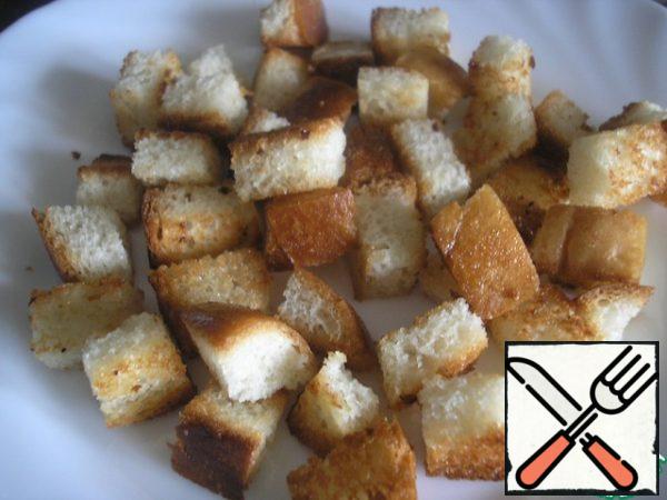 It is very convenient to serve this salad in portions. We will need 4 salad bowls.Prepare the croutons. Cut the slices of the loaf into cubes of about 1x1 cm. Heat 1 tablespoon of oil in a pan.
Over high heat, quickly fry the bread cubes, stirring constantly. Cool them down.
It is important that the crackers turned out with a crispy crust, but soft inside.