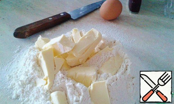 On the work surface sift the flour and throw it into pieces of butter.
Chop the butter with a knife to as evenly as possible it dispersed in flour, but do not get carried away, so it does not melt!
