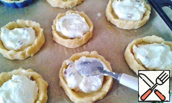 And now it's the turn of the filling: 1.5-2 tablespoons of cottage cheese in each basket, there is not much space, but it can spread during baking.
