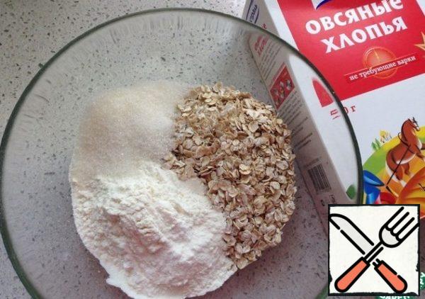 Preheat the oven to 180 degrees. In a bowl, mix oat flakes, flour, sugar and baking powder.