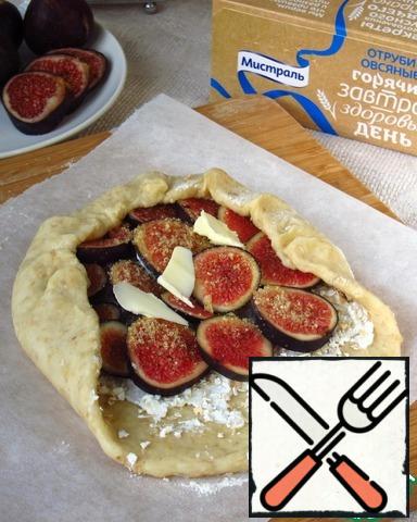 Turn on the oven for heating.
The dough is divided into two parts, each roll out into a flat cake about 15 cm in diameter and 1 cm thick.spread the curd mass on the dough, sprinkle with oat bran ( they will absorb excess liquid), put the figs, sprinkle with brown sugar. The edges of the dough wrap and grease with egg.
In the recipe it was proposed to add a little butter on top, I made one with butter, the second without - there is no difference, so the oil is at your discretion.