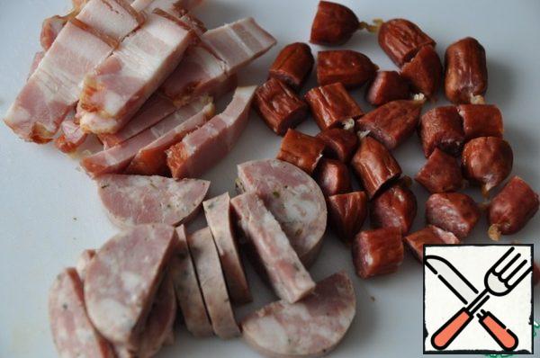 Take meat products. Cut hunting and homemade pork sausages into rings, bacon strips.
