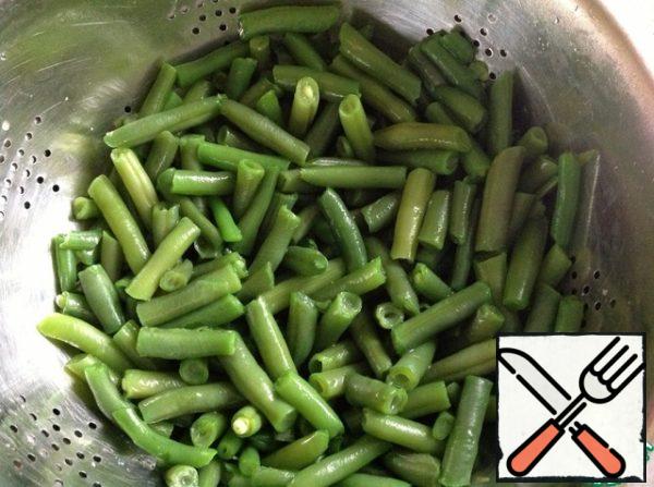 Beans are boiled in salted water and thrown into a colander. Sprinkle with cold water to preserve the color.
