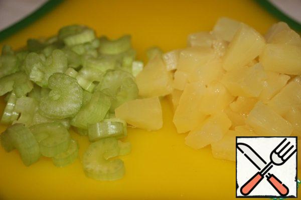 Drain the excess liquid from the tin of canned pineapples, and then cut the slices into small pieces. If you decide to use fresh fruit, first remove the skin from them, and then cut with a knife. Cut the celery stalk not into thick circles.
