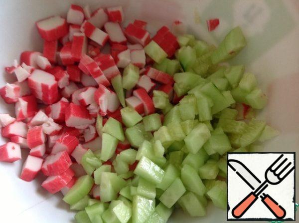 Cut the crab sticks into cubes, peel the cucumber and cut it in the same way as the sticks.
