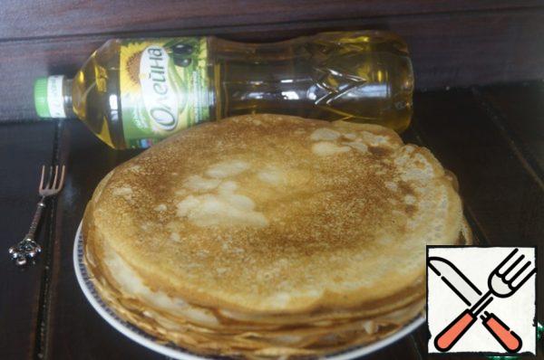 Bake pancakes in a preheated frying pan, greased with a thin layer of sunflower oil. Put the finished pancakes aside.
