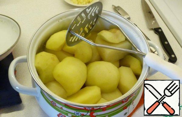 Drain the water from the potatoes. Mash the potatoes by pouring hot cream mixture.
