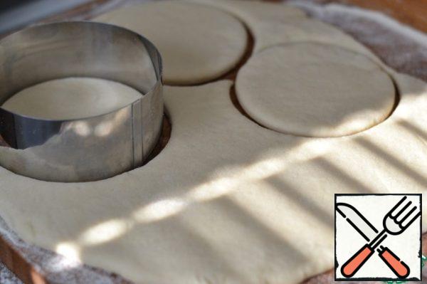 Sprinkle the cutting Board with flour.
Roll out the dough 1 cm tall.
The Cup or mold with a diameter of 10 cm cut out circles.