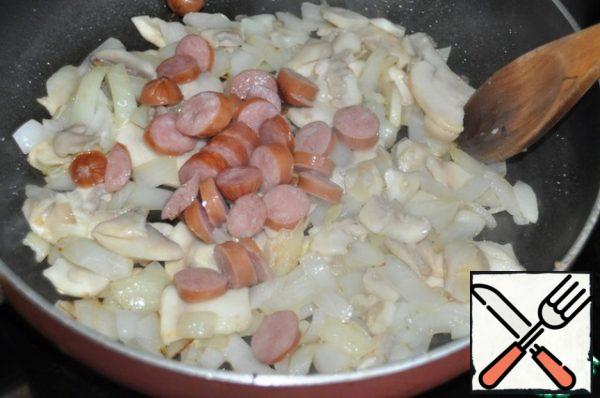 Lay out the hunting sausages cut into rings.
You can add ham or bacon, fry everything and simmer for 8 minutes.