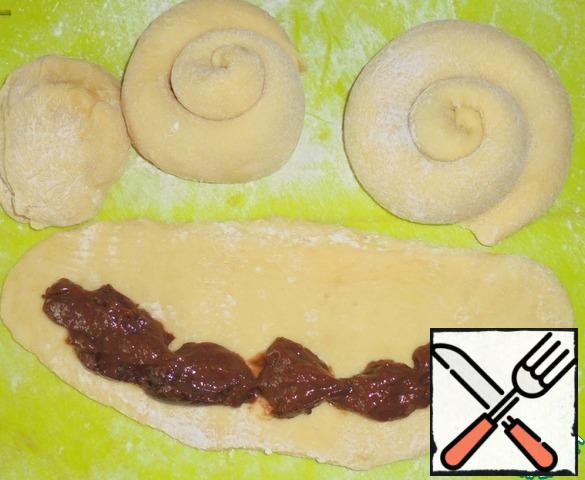 The dough is divided into 10 parts.
Each part is rolled into an oblong strip.
Grease with melted butter.
On the edge of the spread chocolate pudding.
Twist the roll, and then wrap the spiral.