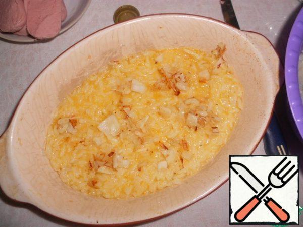 Form for baking grease with oil, put the rice with yolks, top-fried onions.