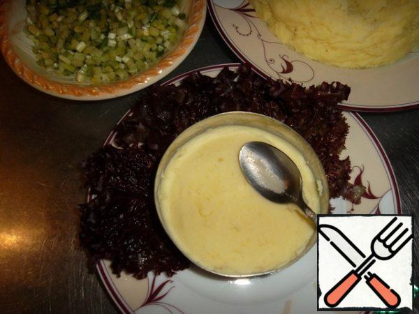 We put lettuce leaves on a plate, put it in a ring and fill it with mashed potatoes up to half.
