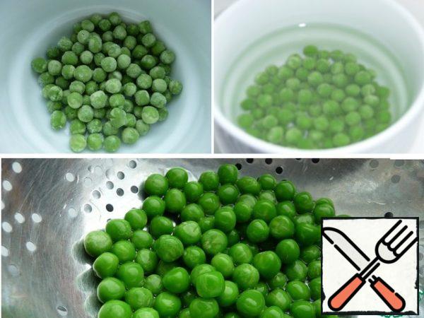 Young green peas from the freezer pour boiling water for 2 minutes, drain, rinse with cold water, immediately throw in a colander. Green peas can be boiled in salt water for a couple of minutes and washed with cold water.