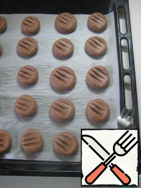 Plucking small pieces of dough, roll the balls (about the size of a half of a walnut). Put them on a baking sheet covered with baking paper. Fork to press down the top.