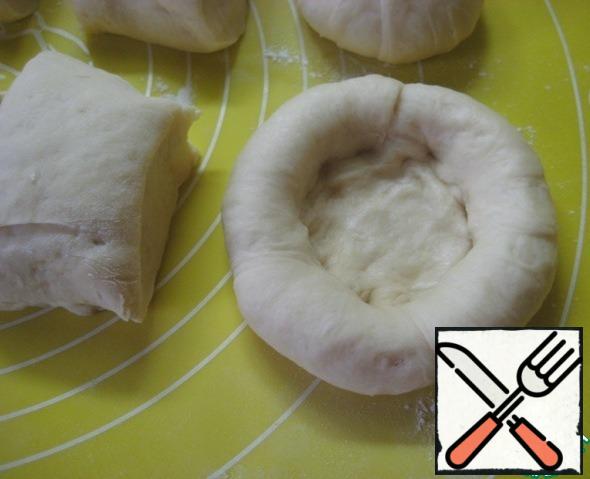 Roll up a piece of dough into a ball, then begin to form a cheese cake, pressing down the center and forming small bumpers.