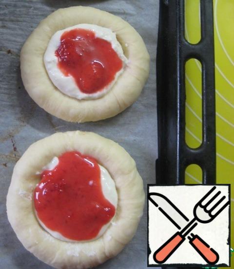 Spread the blanks of cheese cakes on a baking sheet, covered with baking paper. In the recess in the center put about 1 tsp cottage cheese filling, top - 1 tsp strawberry filling.
