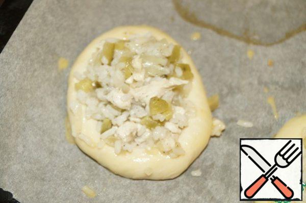 Take one ball and use a glass to make a recess by placing it in the center of the ball and pressing it with the palm of your hand. Put a little filling in its recess. Place the pies on a baking sheet lined with parchment and brush them with beaten egg. Bake at 180 degrees until golden brown.
