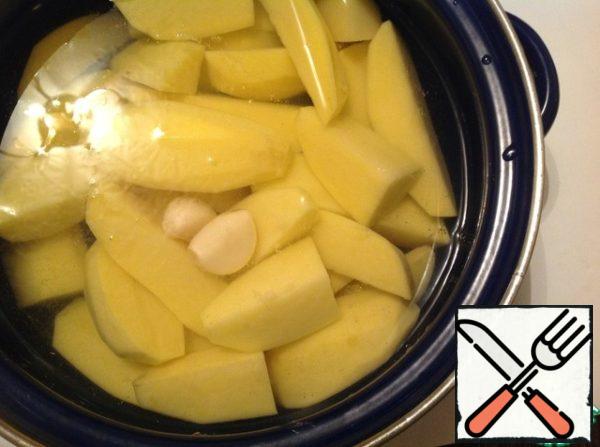 Prepare mashed potatoes. To do this, wash the potatoes, peel, cut into slices, peel the garlic. Add potatoes, whole garlic cloves to a saucepan and cook until tender in salted water. Drain the water, add hot milk or cream, butter and mash.
