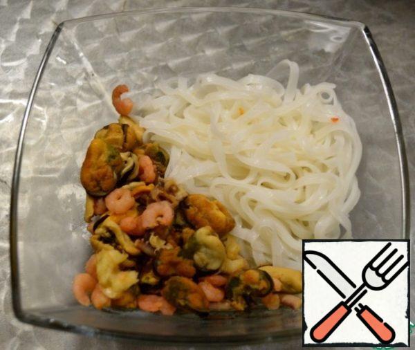 Put the seafood and rice noodles on a plate.
