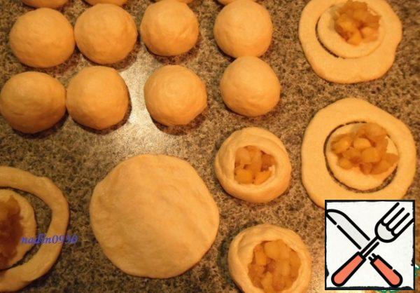 Punch down the risen dough and divide into slices, I got 20 pieces. Pieces of roll up in balls, cover with, to leave on 15-20 minutes. Then roll out each ball into a cake, squeeze out a glass or a form for cookies, put the filling in the middle.