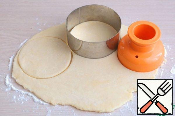 Then roll out the dough to a thickness of 3-5 mm. with a donut blank and a round cookie cutter, cut out the circles.
