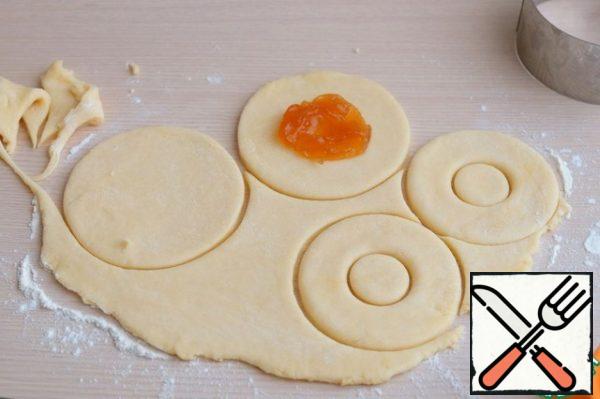 On each circle put 1 teaspoons (heaped) jam, brush with the contour of the exposed surface with beaten egg (to better connect the top ring). Cover the surface with the second ring of dough.