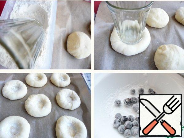 Flatten the balls slightly. Dip the bottom of the glass or mug into the flour (so that the dough does not stick) and press into the middle of each ball.
Fill the frozen currant with starch.