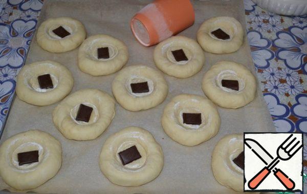 Put them on a baking sheet covered with baking paper. Make a recess in the middle of each ball bottom of the glass, pre-dipping it in flour. In each recess to put a piece of chocolate.