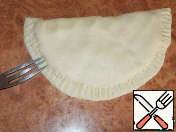 Fold the cake in half, lightly press the palm of your hand on top to let out excess air, and pinch the edges with a fork.
