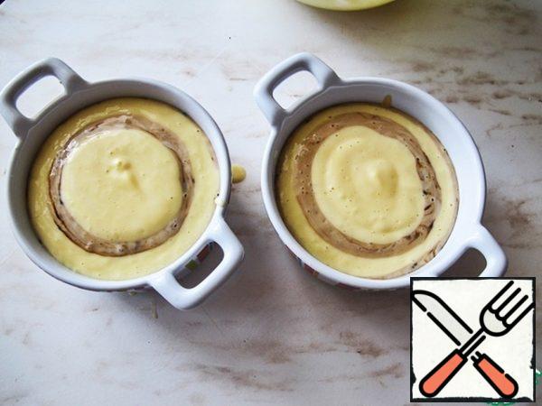 Take small baking molds and cover the bottom with baking paper. With a spoon, mix both types of dough alternately.
