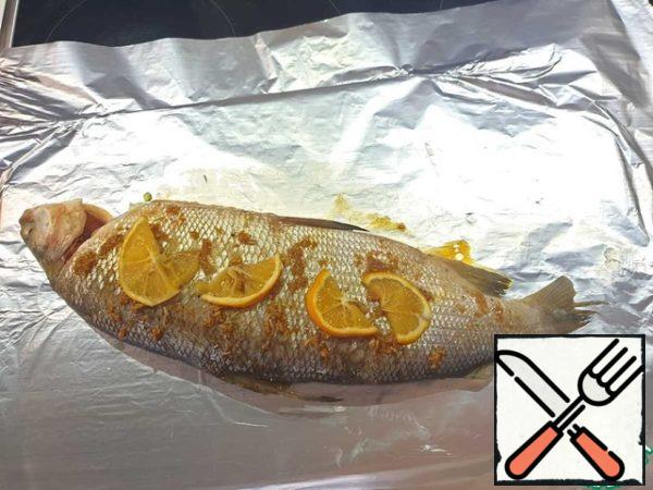On both sides of the outside, brush the fish with the remaining sauce and spread with the remaining lemon. Cover tightly with foil and put in the oven for 20-25 minutes (the baking time may depend on the size of the fish).
