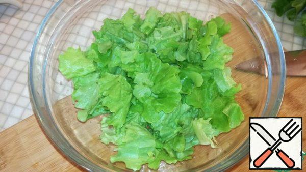 Wash the lettuce leaves, shake off excess moisture and cut into small pieces. Pour into a salad bowl. This will be the first layer.
