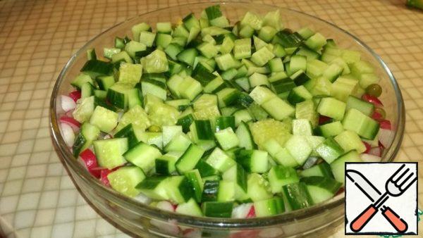 Cut the cucumber into cubes and put it in a salad bowl.
