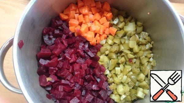 Boil the carrots and beets, peel and cut into cubes. Cut the pickled cucumber into cubes.
