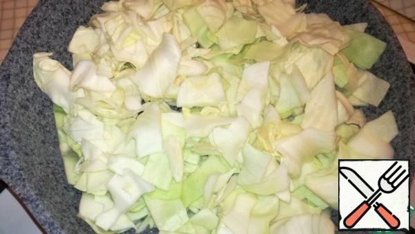 Cut the cabbage into large squares. Pour sunflower oil into a preheated frying pan and pour out the cabbage. Fry for 10 minutes.
