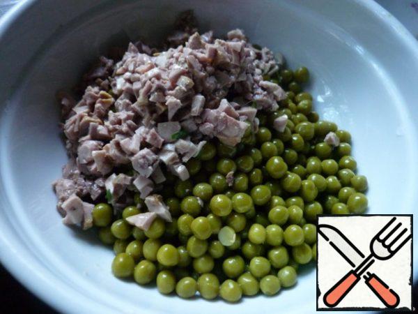 Drain the water from the green peas, put the peas in a salad bowl. Add finely chopped cod liver.
