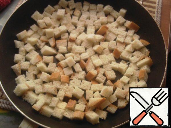 Prepare the croutons: 5 Kus. cut the white loaf into cubes, dry in a heated pan, put on a plate and squeeze out a couple of slices of garlic and season with 1 tablespoon of oil.