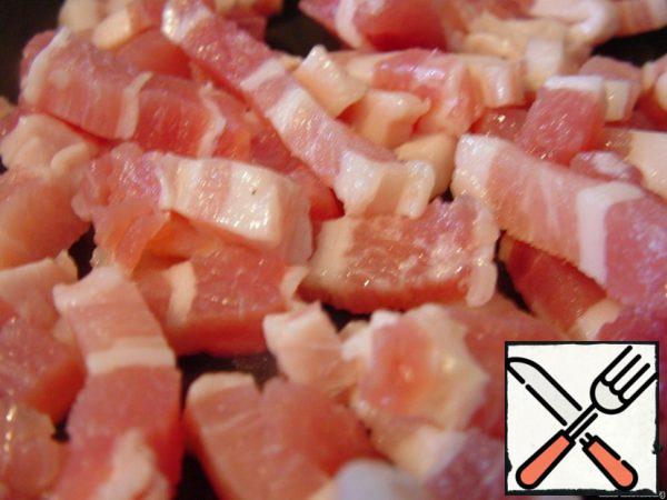 At this time, cut the bacon into cubes and fry until Golden brown. I love it when it gets crunchy, but it's a matter of taste.
When the wine boils, add vegetables, broth and salt and pepper as needed. Cover with a lid and cook until tender.