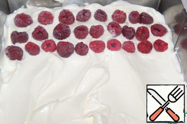 Spread the cream over the entire surface of the baked cake and slightly drown in it frozen raspberries.