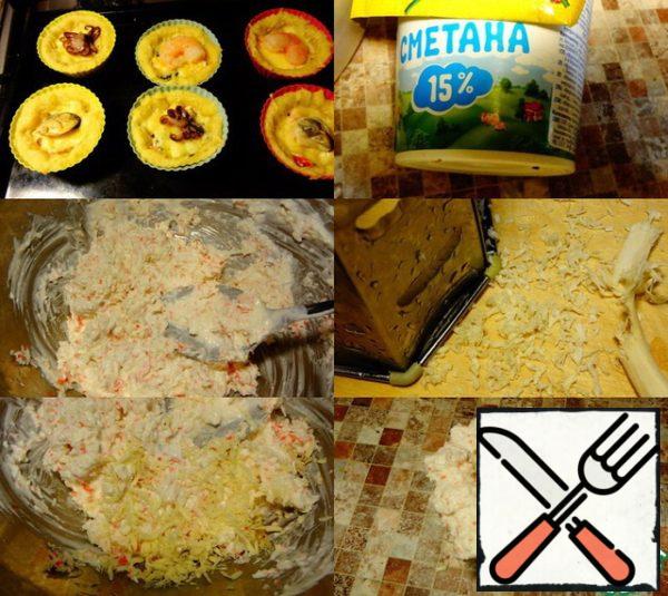 Put the form for tartlets in preheated to 200 gr. Bake in the oven for 15 minutes. then take it out and put it on top of the seafood.
One for each form. Put it in the oven for another 10 minutes.
While the tartlets are being baked, you need to prepare a cream for decoration..
To do this, rub the remaining crab sticks on a fine grater. Add to them 3 tablespoons of sour cream and finely grated fresh horseradish.
Mix the cream.
When the tartlets are ready, decorate them around the edge with the prepared cream and parsley leaves.
