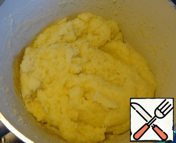 Mix milk and water in a saucepan, add 100 g of butter, boil.
Immediately pour in all the flour and knead the dough quickly. Reduce the heat to a minimum and knead until all the dough comes together in one lump and does not lag behind the bottom and walls of the saucepan.